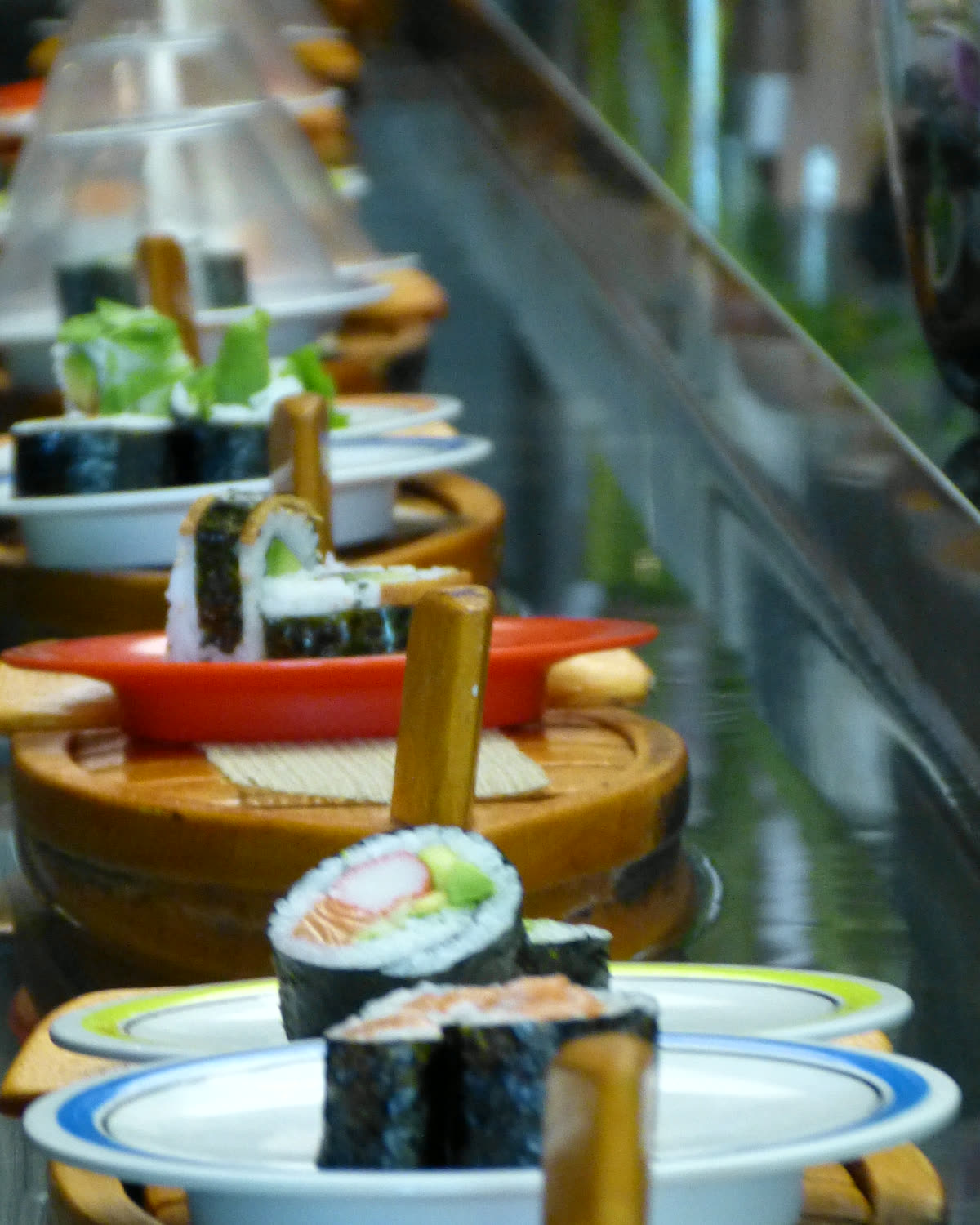 Running Sushi auf einem Wasserband mit kleinen Schiffchen, Maki-Sushi, Nigiri-Sushi und Desserts